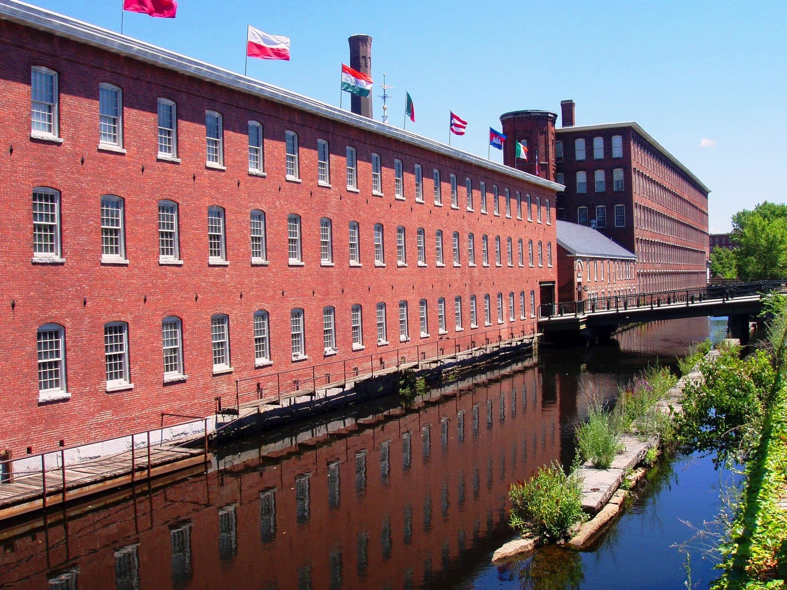 Red brick textile mill along a canal in Lowell, Massachusetts, the kind of factory where the mill girls in the essay struck over wage cuts, for a 7/7 AP US History DBQ essay