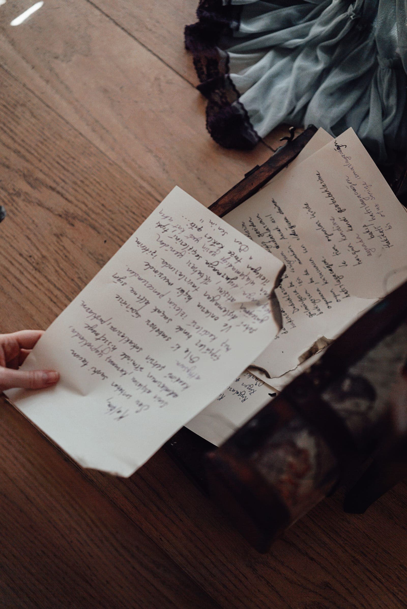 A handwritten 18th-century-style letter held above an old wooden box, evoking founding-era correspondence like Abigail Adams' "Remember the Ladies" letter discussed in this AP US History LEQ.
